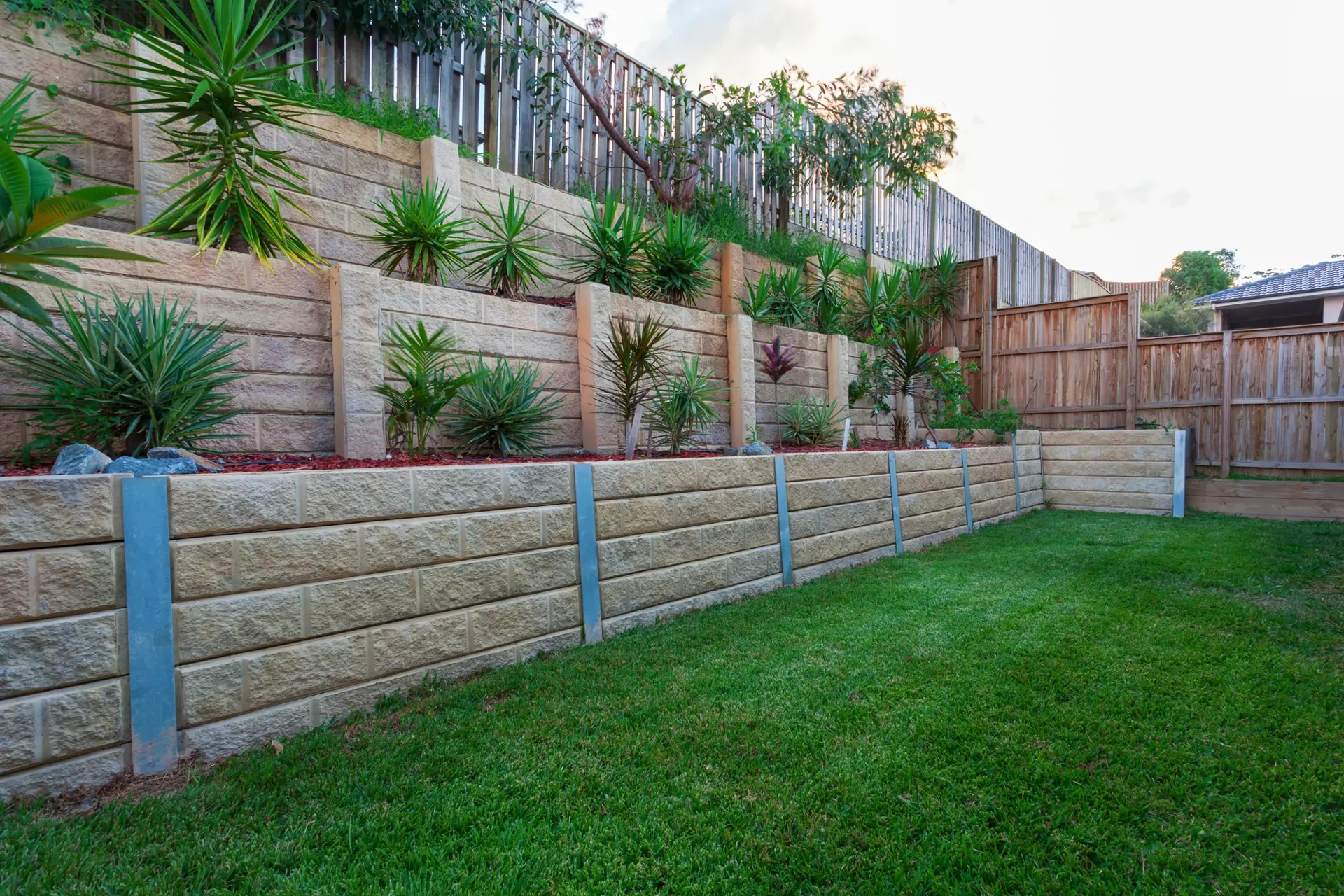Tiered concrete retaining walls with garden beds stepping up a backyard slope