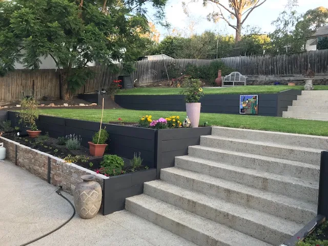 Charcoal concrete sleeper retaining walls with wide concrete steps through a terraced garden