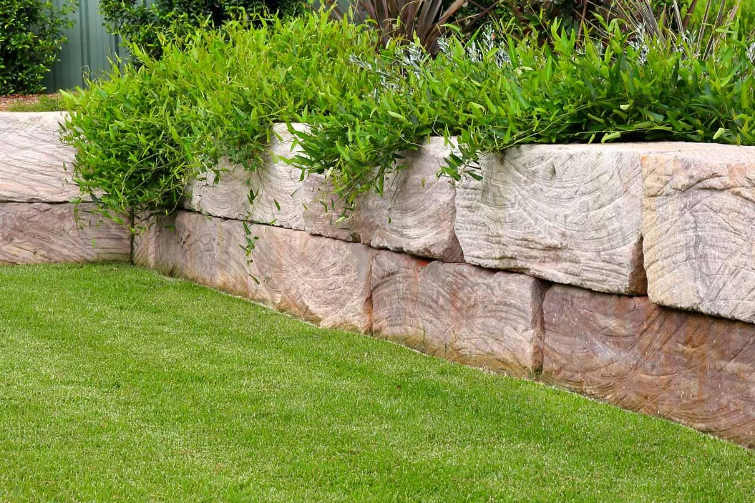 Sandstone block retaining wall with a garden bed above a lawn