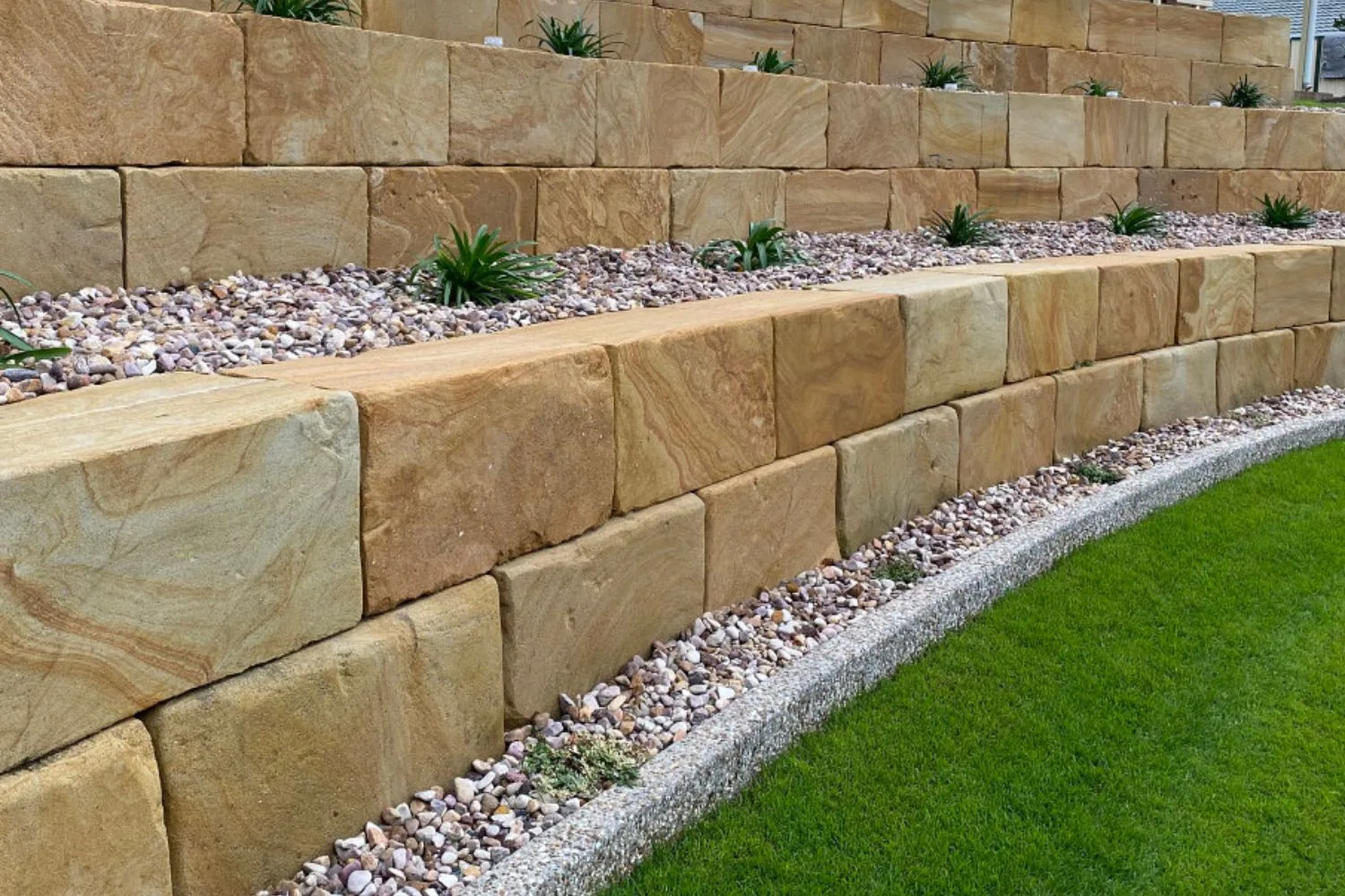 Terraced sandstone block retaining walls with a gravel border and lawn